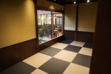 チェッカーフロア風の床材を使用したロビー。奥に引き戸と掲示板が見える。